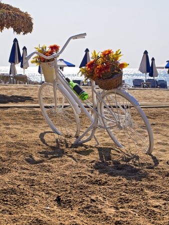bicycle parked on a beach next to the sea umbrellasの写真素材