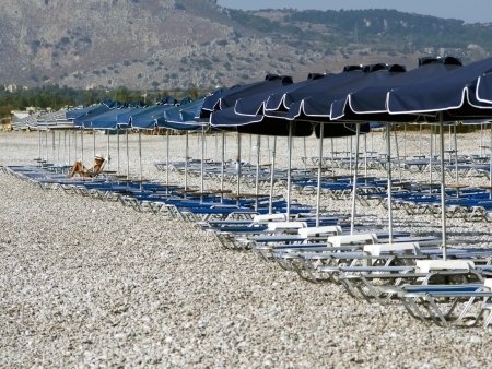 woman sunbathing on a lounger by itself between the umbrellas emptyの写真素材