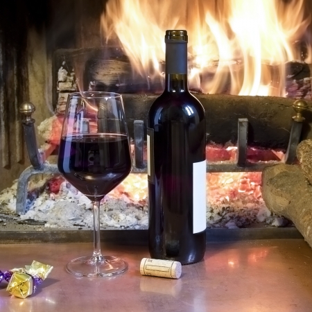 celebrate with a glass of wine, a bottle, in front of a fireplaceの写真素材