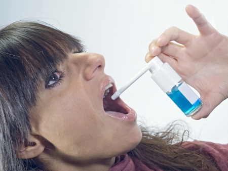 woman with a spray dispenser for sore throatの写真素材