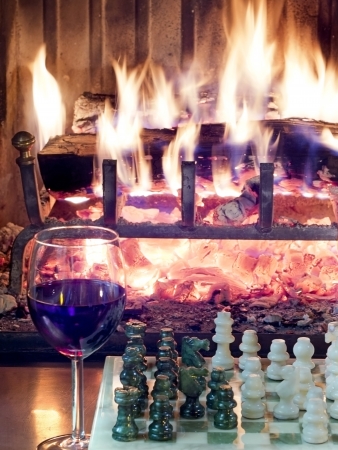 play chess drinking red wine in front of a roaring fireplaceの写真素材