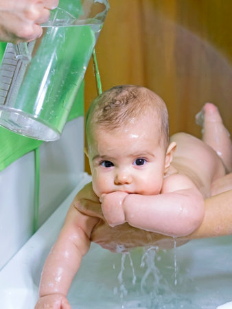 baby girl washed during bathing supported by her momの写真素材