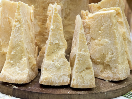 thick slices of Italian Parmesan cheese on a wooden cutting boardの写真素材