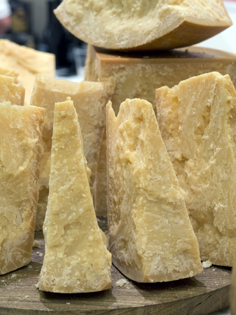 thick slices of Italian Parmesan cheese on a wooden cutting boardの写真素材