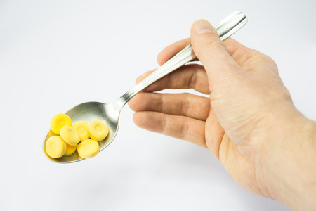 a hand lifts a spoon full of medicineの写真素材