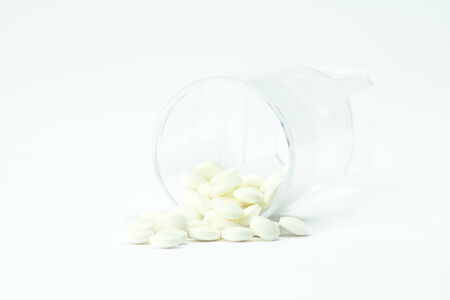 white pills out of container on white background