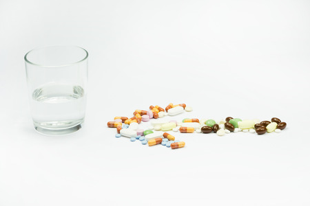 arrow pills near a cup of water on white backgroundの写真素材
