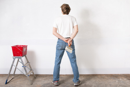man painting a wall white with paint brushの写真素材