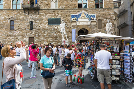 Florence,Italy-august 26,2014:many tourists in Piazza della signoria take pictures, buy souvenirs or enter in the Palazo vecchio during a sunny day.Palazzo vecchio in one of the symbols of Florence.のeditorial素材