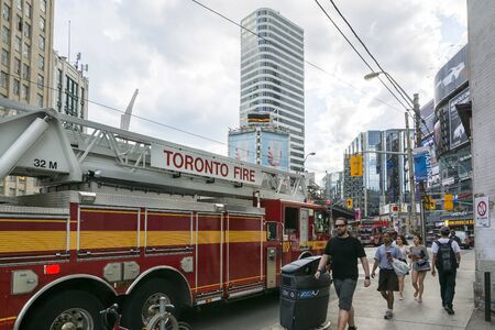 Toronto,Canada-august 1,2015:A fire truck passes through the crowd of toronto while walking or traveling to work in the suburbs of Toronto during a cloudy day.のeditorial素材