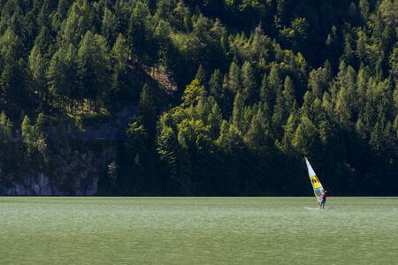 Alleghe,Italy-August 22,2016:Man makes windsurfing on the beautiful lake of Alleghe between the Italian Dolomites.のeditorial素材