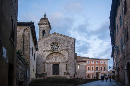 San Quirico d'Orcia,Italy-april 24,2016:people stroll near the church in the  San Quirico town square during a cloudy day.のeditorial素材