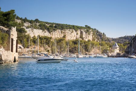 Cassis,France-august 10,2016:The port of inside a creek near Cassis,a French village with colorful boats moored and the lighthouse during a summer day.のeditorial素材