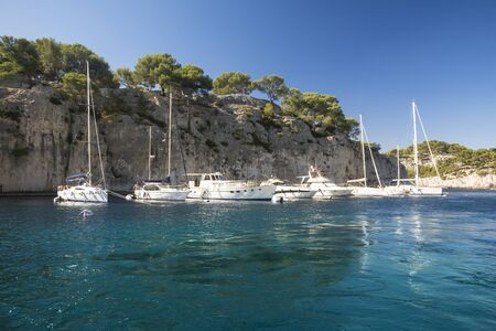 Cassis,France-august 10,2016:The port of inside a creek near Cassis,a French village with colorful boats moored and the lighthouse during a summer day.のeditorial素材