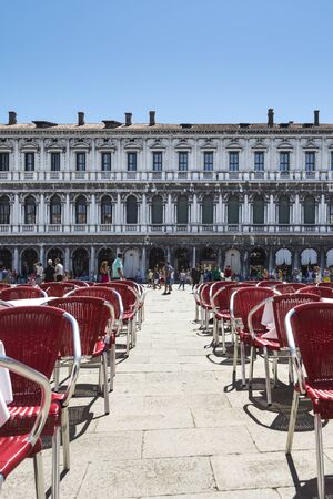 Venice,Italy -August 17,2014:people stroll in the famous saint Mark square in Venice near the bar with the red chairs during a sunny day.のeditorial素材