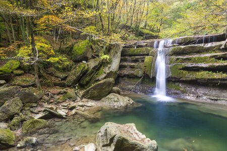 Waterfall in a forest with autumn colors in Italyの写真素材