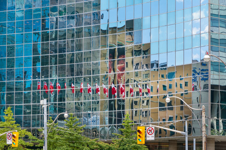 Toronto,Canada-august 3,2015:flags of Canada reflected on the glass surfaces of Toronto's many skyscrapers during a summer dayのeditorial素材