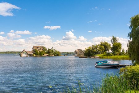Thousan islands,Canada-august 4,2015:classic cottage with moored boatt on the banks of the St. Lawrence River in One thousen islands national park in Ontario during a summer dayのeditorial素材
