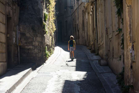 Arles,France-august 14,2016:unrecognizable child with backpack strolls through the narrow streets of Arles on a sunny dayのeditorial素材