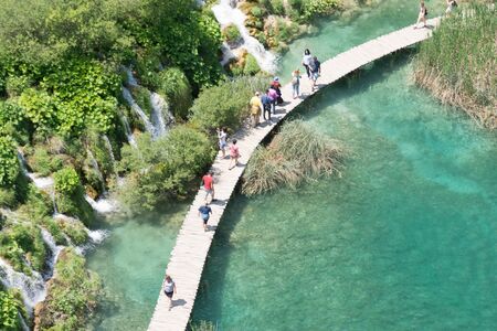 top view of people on classic wooden walkways crossing lakes in Plitvice natural park during a sunny dayの写真素材
