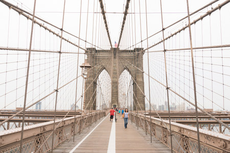 New York City, USA - August 6, 2019: People walk across the famous Brooklyn Bridge during a cloudy day.のeditorial素材