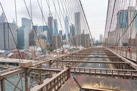 New York City, USA - August 6, 2019: People walk across the famous Brooklyn Bridge during a cloudy day.のeditorial素材