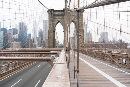 New York City, USA - August 6, 2019: People walk across the famous Brooklyn Bridge during a cloudy day.のeditorial素材