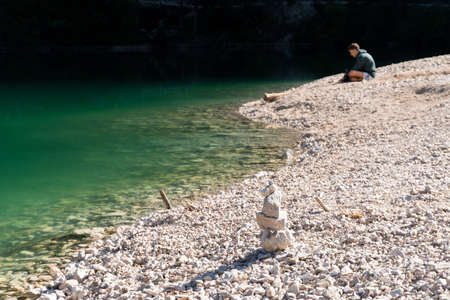 Braies, Italy-September 10, 2021: boy sitting on the shore of Lake Braies in the province of Bolzano admires the mountains that surround him during a sunny dayのeditorial素材