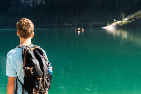 Braies, Italy-September 10, 2021: boy on the shore of Lake Braies in the province of Bolzano admires the mountains that surround him during a sunny dayのeditorial素材