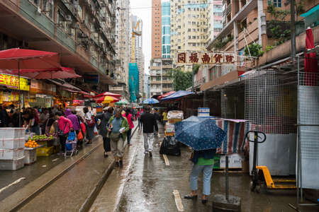 Hong Kong, March 24,2019: People among the classic markets in the narrow and crowded streets of Hong Kong during a raining dayのeditorial素材