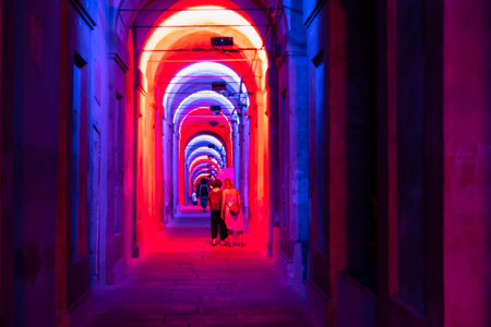 Bologna,Italy- June 23, 2023:People stroll at night under the arcades leading to the sanctuary of...
