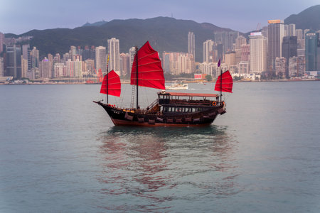 Hong Kong,March 25,2019:View of the Hong Kong skyscrapers and traditional boat from the Avenue of star on the Victoria Harbor during a cloudy dayのeditorial素材