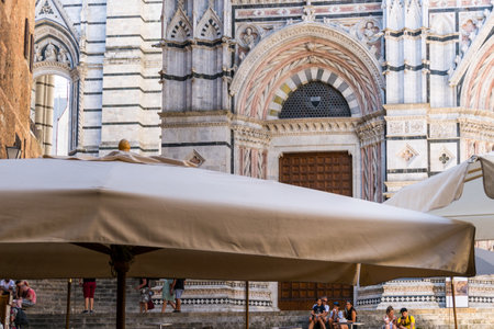 Siena ,Italy-august 10, 2020:Tourists between the Cathedral and the Baptistery of San Giovanni battista during a summer day in Sienaのeditorial素材