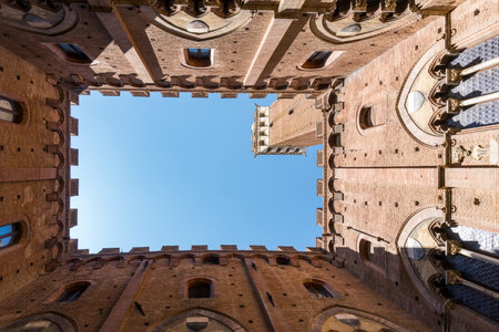 Siena,Italy-August 10, 2020:view of the Mangia tower in piazza del campo from the internal courtyard of the civic museum during a sunny dayのeditorial素材