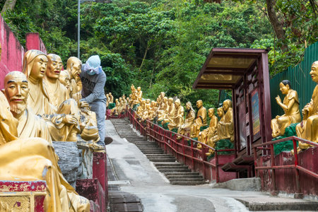 Hong Kong,March 27, 2019:people cleaning the Buddha statues leading to the famous Ten Thousand Buddhas Monastery during a cloudy dayのeditorial素材