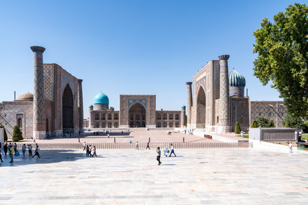 Samarkand, Uzbekistan-August 12, 2023:People visit the Registan square occupied by a large complex made up of 3 madrasas famous for the purity of the lines and the elegance of the majolica during a sunny dayのeditorial素材
