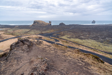 Reykjanes peninsula, Iceland-March 17, 2025:road leading to the coast seen from the hill of the Reykjanes Lighthouse on a cloudy dayの写真素材