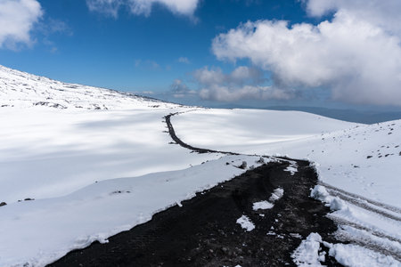 Dirt road in the snow on Mount Etna in Sicily on a sunny dayの写真素材