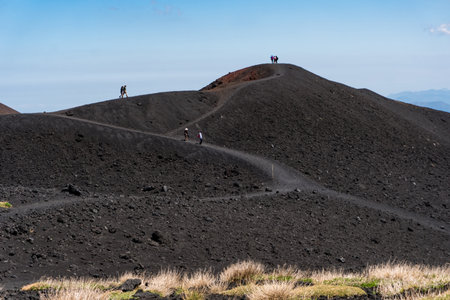 People on the paths that cross some craters of the Etna volcano during a sunny dayの写真素材
