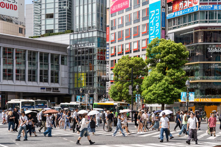 Tokyo, Japan-August 7, 2024:A crowd of people, many with umbrellas to shield themselves from the...