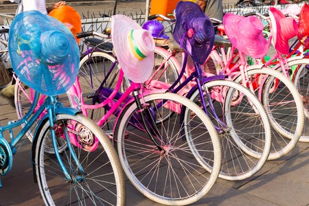 Colorful bicycles with lady hats is parking in a row waiting for rented.