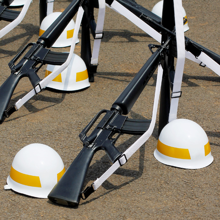 Formation of assault rifles and yellow striped helmets laid on the ground.の写真素材