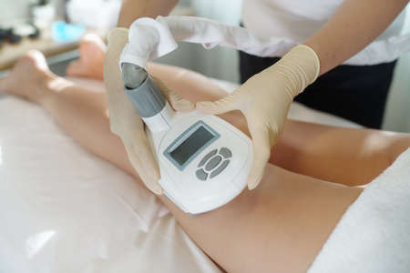 The nurse performs the manipulations with the lymphatic drainage apparatus on the woman hips, doing...