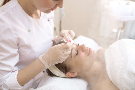 The beautician cleans the patient's face by steaming the pores of the skin with steamの写真素材