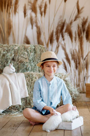 Cute farm girl hugs and feeds her little white rabbits: Easter themeの写真素材