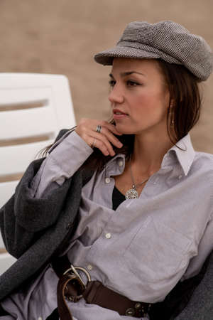 A beautiful young brunette woman walks on the beach in cool weather in a fashionable outfitの写真素材