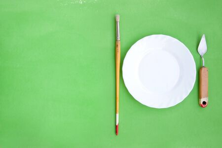 Artistic bright green background with a brush, palette knife and a plateの写真素材