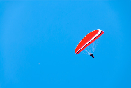 A red hang glider soars through a deep blue sky.の写真素材