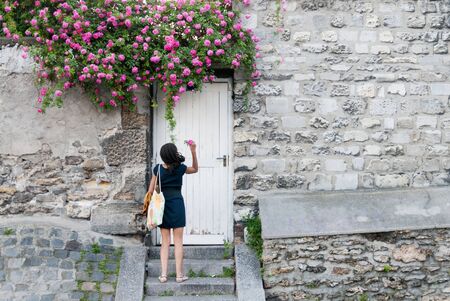 PARIS-JUNE 2: An unknown young woman picks a rose from a garden wall on June 2, 2009. As a top business and cultural center, Paris is one of the most visited cities in the world.のeditorial素材
