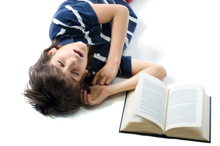 Young boy falling asleep while studying on school book, isolated on whiteの写真素材